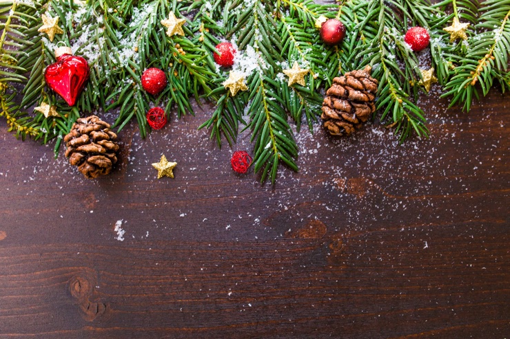 Cosy image of a table scattered with pine cone and fronds, fake snow and baubles