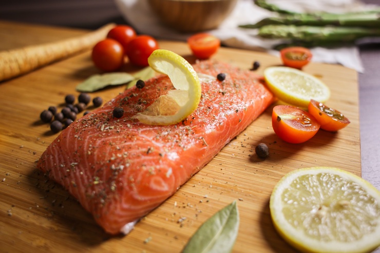 Colourful photograph of fresh salmon fillet with cherry tomatoes, lemon, seasoning and veg