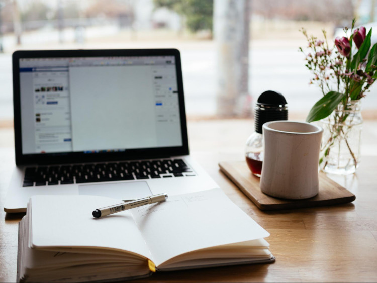 Open book and pen sitting in front of a laptop