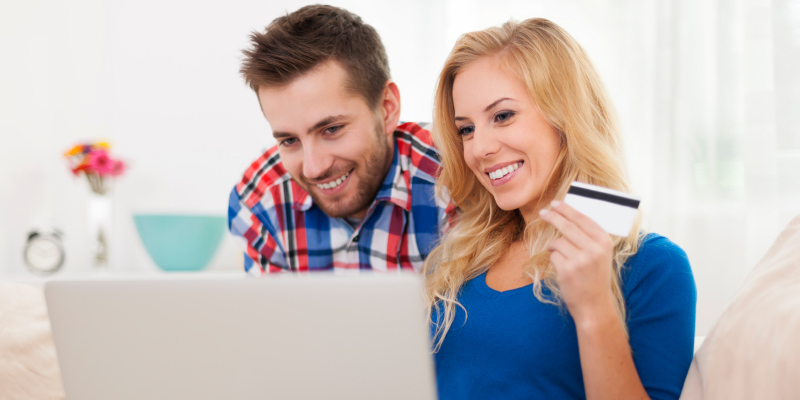 Two people looking at a laptop with a credit card in hand