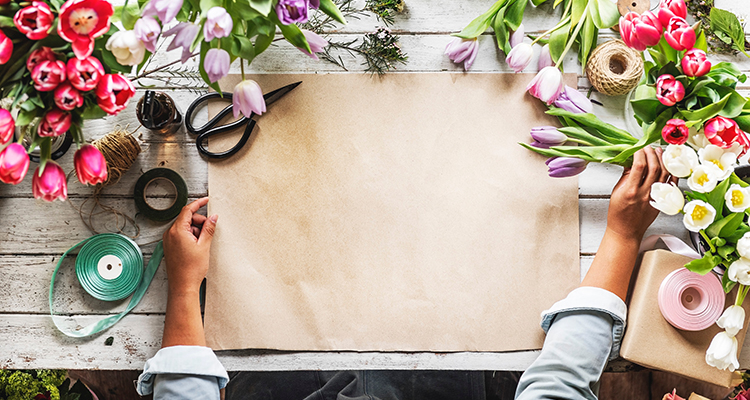 Florist preparing to wrap a bouquet on a wooden desk