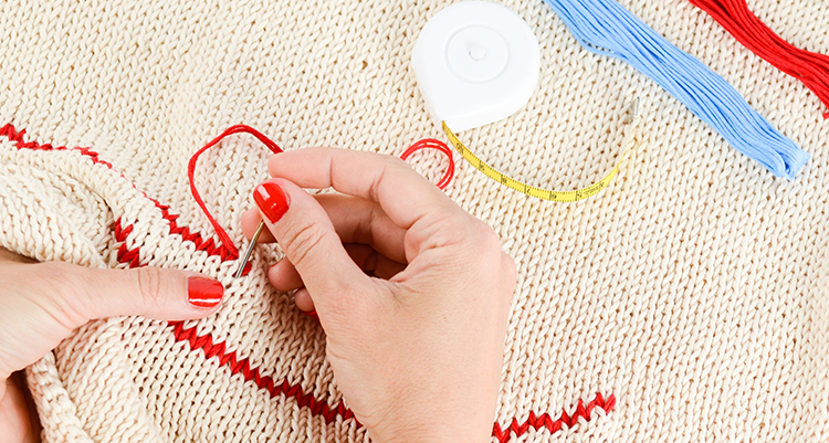 Person sewing red thread through material