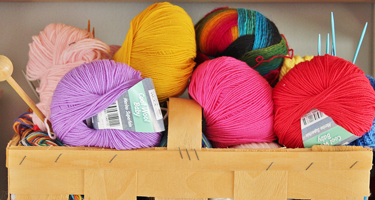 Balls of wool and knitting needles sitting in a basket