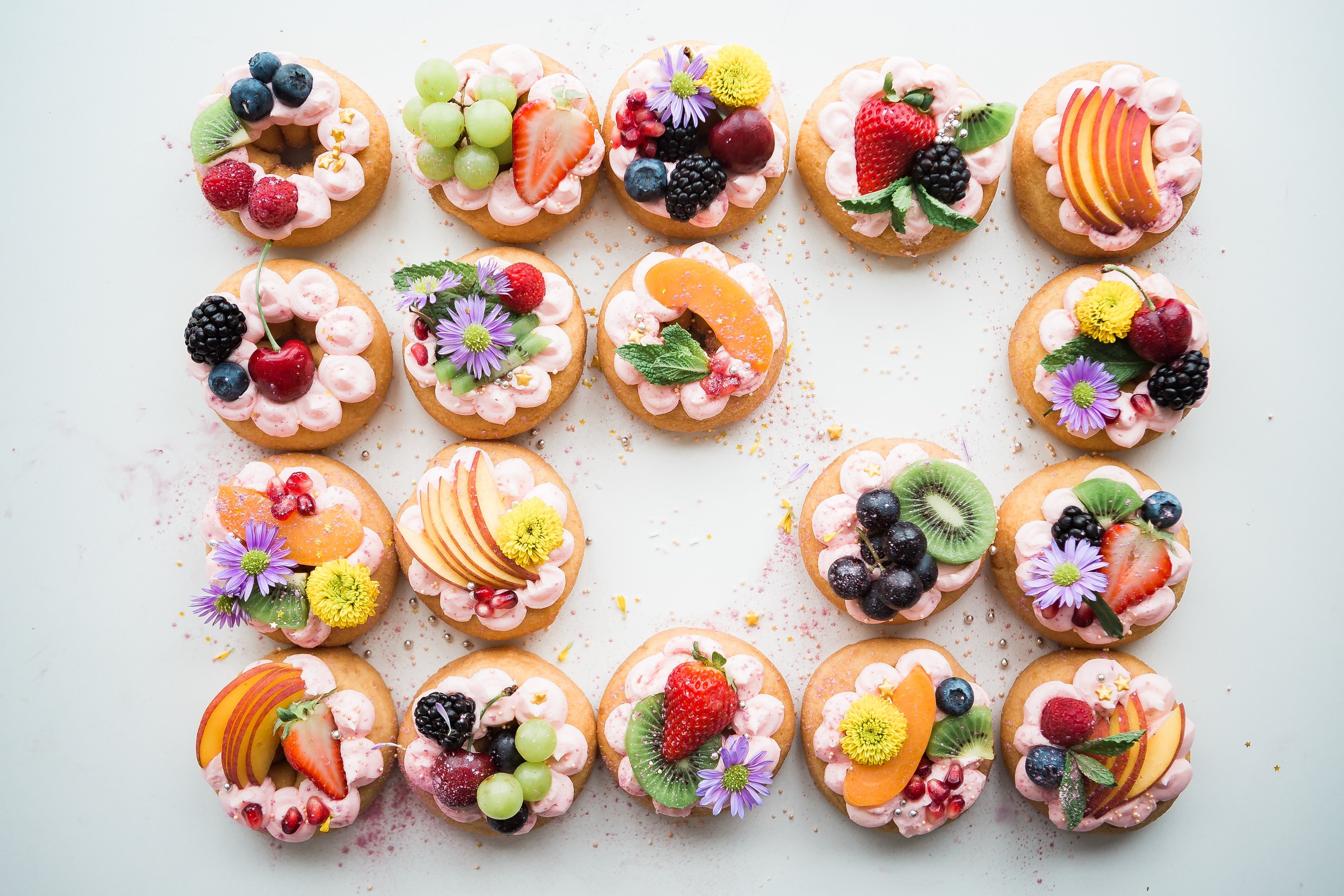 A grid of vibrant and elaborate fruit tarts with two tarts missing