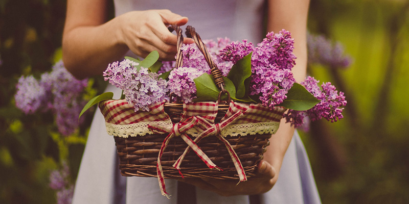 A person holding a wicker basket full of flowers