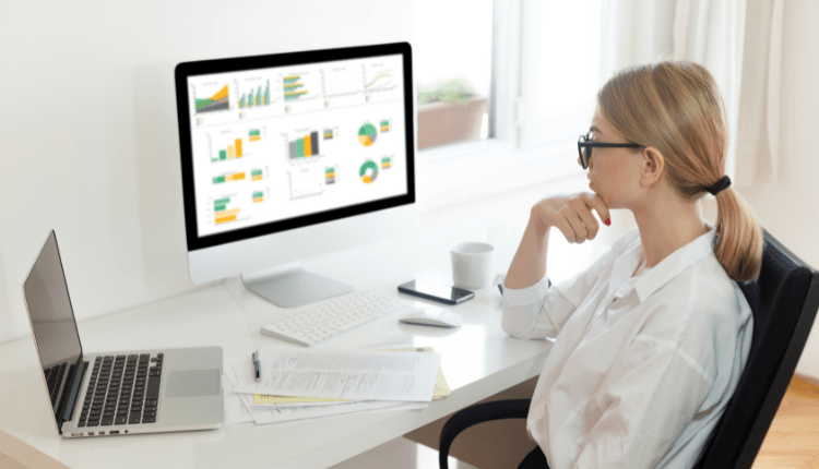 A person analysing charts and graphs at their desk on the computer